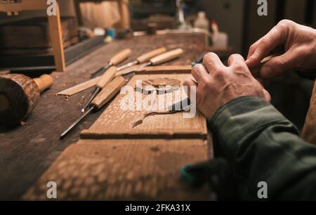 Close up of cabinetmaker working on a wood carving with a chisel. Stock Photo