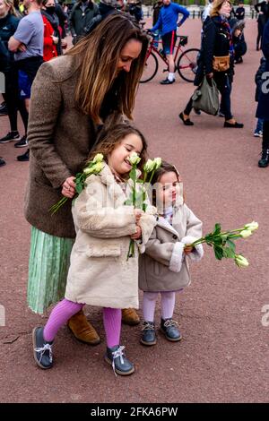 A Family Pays Their Respects To Prince Philip Who Recently Passed Away By Laying Flowers At The Gates Of Buckingham Palace, London, UK. Stock Photo