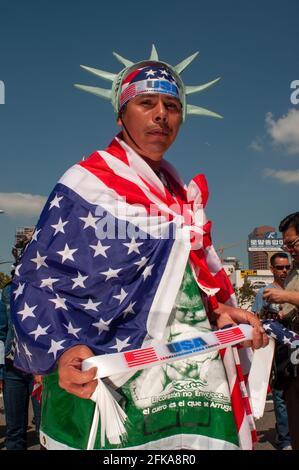 A patriotic man with American flags and a Lady Liberty crown poses for a picture at a immigration rights protest in Downtown Los Angeles. Stock Photo
