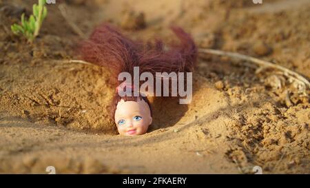 Smiley face of Baby doll with attractive red blond hair. Rubber doll closeup for kids. Childhood concept. Stock Photo