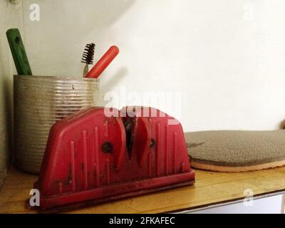 Red vintage knife sharpener on old wooden table Stock Photo