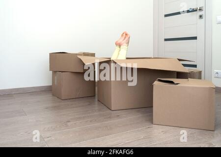 baby's feet are sticking out of the cardboard box. moving to a new house Stock Photo