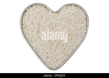 Heart shaped tin pan full of raw white Sticky rice, also called Glutinous rice grains grown in Roi-et, Northeast of Thailand, isolated on white backgr Stock Photo