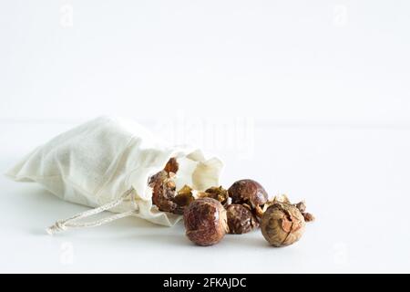 Soap nuts falling out of linen bag on white background; organic laundry detergent; eco-friendly Stock Photo