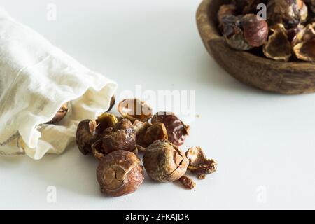Soap nuts falling out of linen bag on white background; organic laundry detergent; eco-friendly Stock Photo