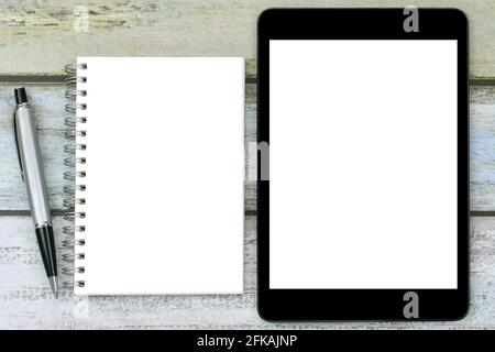 Blank notebook with a silver pen next to black tablet computer with white blank screen Stock Photo