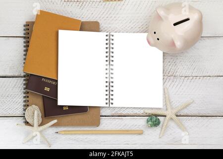 Top view of pink piggybank on blank white notebook with passports and a pencil on wooden background, conceptual idea for planning a trip Stock Photo