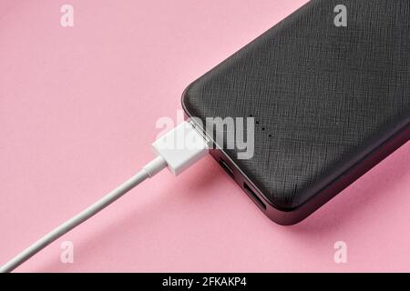 USB connector is connected to Power bank on a pink background. Charging gadgets. Close-up, selective focus Stock Photo