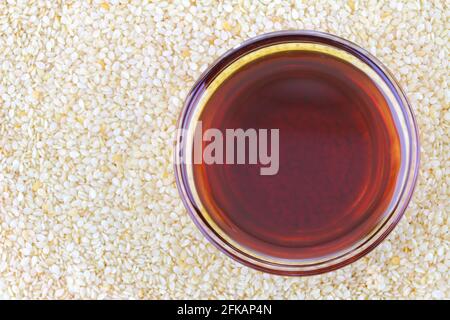 A bowl of cold pressed Sesame oil on white sesame seeds background Stock Photo