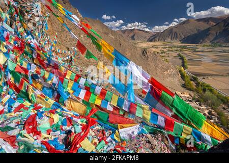 Buddhist prayer flags near the Yungbulakang Palace or Yumbu Lakhang, high on the Tibetan Plateau in the Himalayas in the Tibet Autonomous Region of Ch Stock Photo