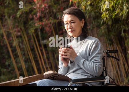 A lonely old woman in the yard in the sun Stock Photo