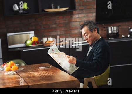 Recreational older men sitting at home reading a newspaper Stock Photo