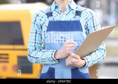Woman builder in overalls holding clipboard and ballpoint pen closeup Stock Photo