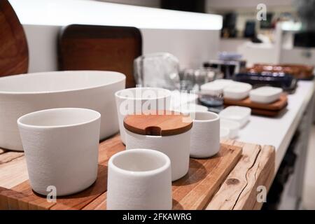Ceramic or porcelain tableware on wooden pedestal on store shelf. Stock Photo