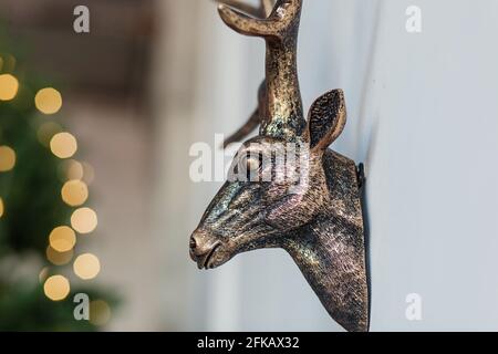 decorative deer head hanging on the wall against the background of Christmas lights Stock Photo