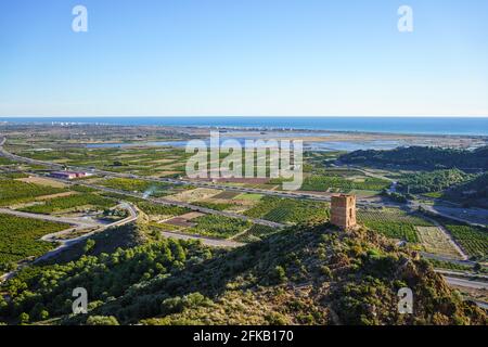 Mediterranean coast landscape on sunny day. Ruined watchtower at the top of a hill,agriculture fields,wetlands in Almenara,Castellon,Spain Stock Photo