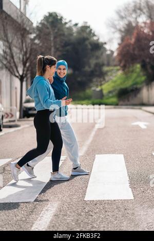 Cheerful active girls wearing sports clothes walking and crossing