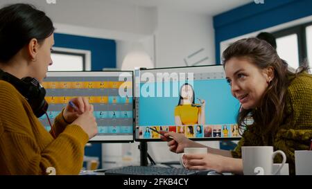 Art director teaching retoucher employee how to color gread female portret using photo editing software. Graphic designers analysing client assets from displays and taking notes in creative agency Stock Photo