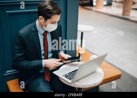 Businessman using smart phone with laptop in cafe Stock Photo