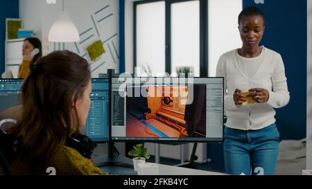 Diverse women game sofware developers testing new game sitting in startup creative agency company using pc with dual monitors setup. Workers developing new online video games with modern technology Stock Photo