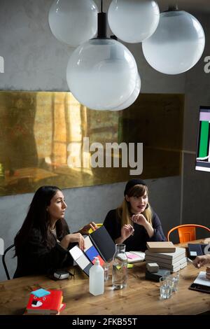 Happy female colleagues discussing over product during meeting at creative office Stock Photo