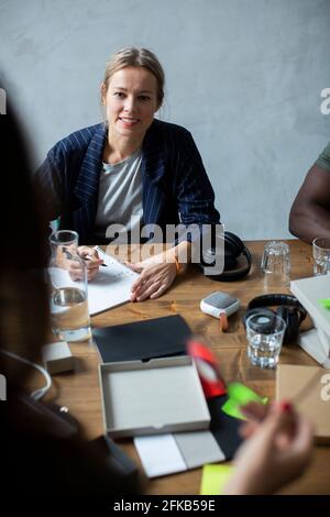 Smiling businesswoman discussing with colleague at desk in office Stock Photo