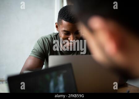 Smiling businessman working on laptop in office Stock Photo