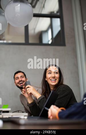 Smiling businesswoman talking with colleagues during meeting at office Stock Photo
