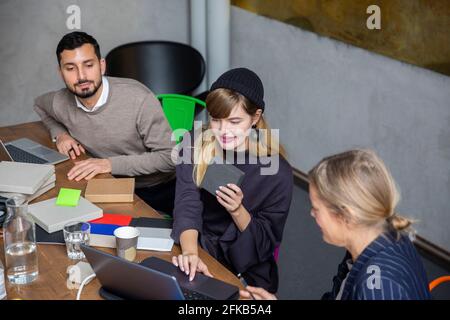 Businesswoman using laptop while discussing with male and female colleagues at creative office Stock Photo