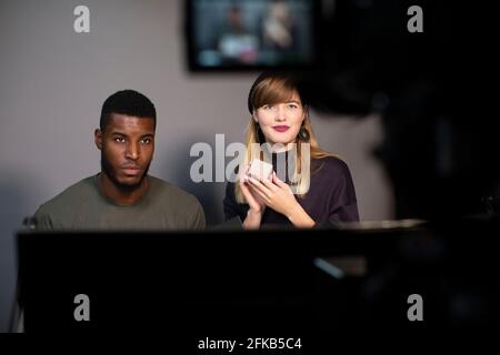 Female entrepreneur showing product by male colleague recording on camera Stock Photo