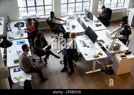 Businesswoman smiling while male and female colleagues working on laptop at office Stock Photo