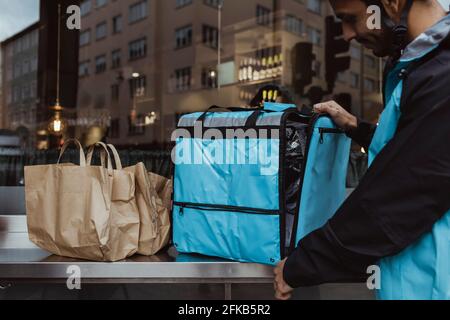 Deliver man standing by backpack outside deli store Stock Photo