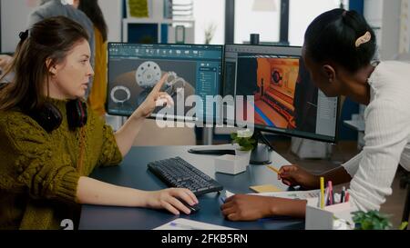 Gamer creator explaning to african worker how testing game level interface, developing new design in creative office using pc with two monitors. Player online video games with technology network wireless. Stock Photo