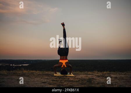 Young female athlete practicing yoga during sunset Stock Photo