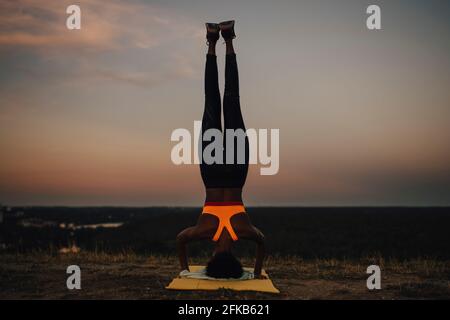 Sportswoman practicing yoga during sunset Stock Photo