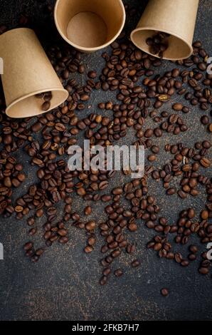 craft paper cups for coffee and coffee beans on dark concrete background. The concept of hot drinks take away, Invigorating breakfast. Stock Photo