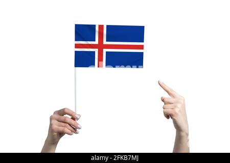 A beautiful female hand holds a Iceland flag to which she shows the finger of her other hand, isolated on white background. Stock Photo