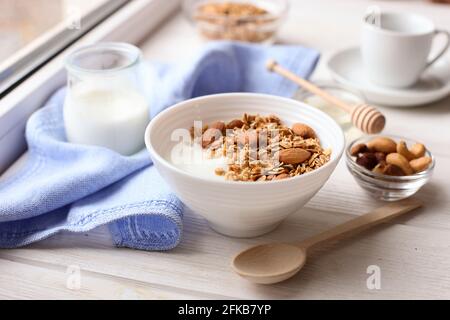 Healthy breakfast. Yogurt with granola and nuts on window sill Stock Photo
