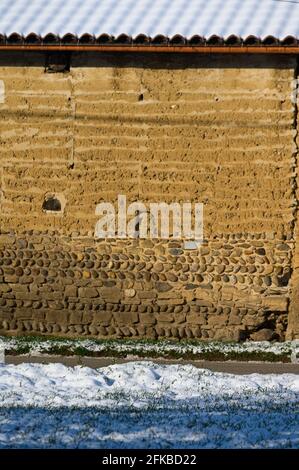 A brown colored wall made up of or covered with mud or dirt to keep the interiors of the house cool. Stock Photo