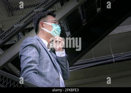 Asian businessman adjusting his face mask as he puts on his face. Stock Photo
