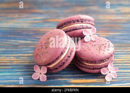 French blueberry macaroons sweets & lilac purple flowers on multi color grunge timber wooden texture table background. Birthday valentine present. Cop Stock Photo
