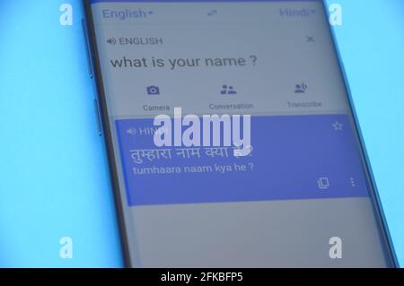 Mandi, Himachal Pradesh, India - 03 05 2021: Translating "What is your name" English to Hindi language on Google translate displaying on mobile phone isolated on blue colored background. Stock Photo