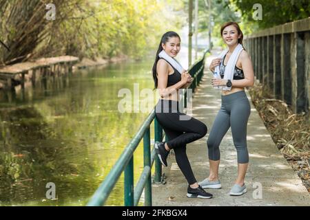 Portrait healthy Asian adult women standing together friendly look waring sport cloth in the morning. Stock Photo