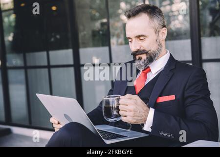 Hispanic latin businessman beard happy enjoy working with laptop computer relax at cafe drinking hot coffee Stock Photo