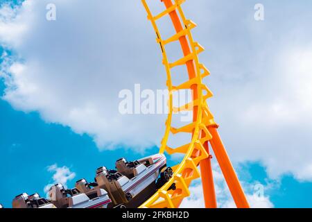 roller coaster high in the summer sky at theme park most excited fun and joyful playing machine Stock Photo