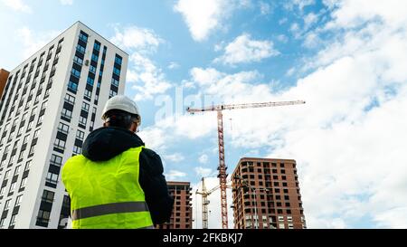 Consulting engineer at construction site holding blueprint in hand. Construction inspector. Construction site inspection drawing and new building work Stock Photo