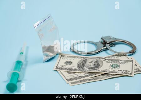 A bag of drugs, US dollars and handcuffs on the table. Concept - punishment for possession of narcotic drugs. Copy spase, spase for text. Stock Photo