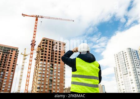 Consulting engineer at construction site holding blueprint in hand. Construction inspector. Construction site inspection drawing and new building work Stock Photo