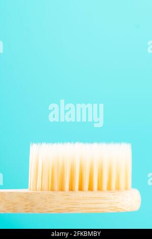 Eco friendly natural bamboo toothbrush on a blue background. Bristles of a bamboo toothbrush close-up. Health care, copy space. Stock Photo