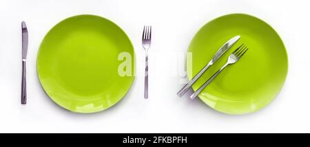 Served plates with cutlery. Empty green plates and stainless knives and forks isolated on white background. Top view Stock Photo